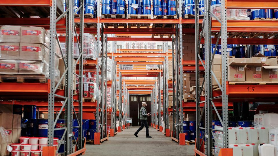 Interior de almacén logístico con estanterías industriales y mercancía almacenada en entorno empresarial B2B.